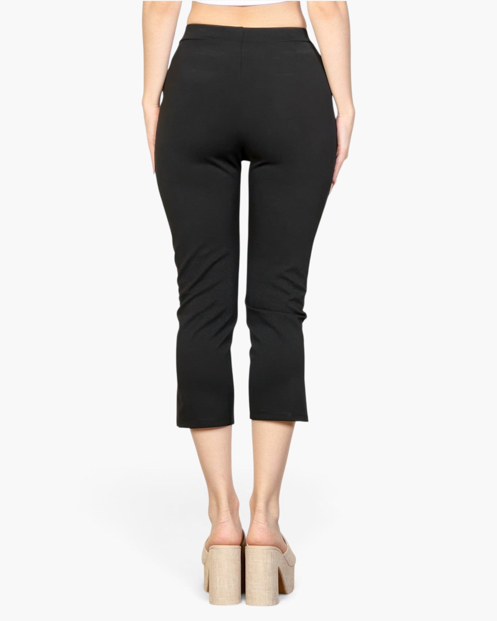 Beach Rose Co. black cropped pants with slit hem detail, worn by a model with platform mules, back view.