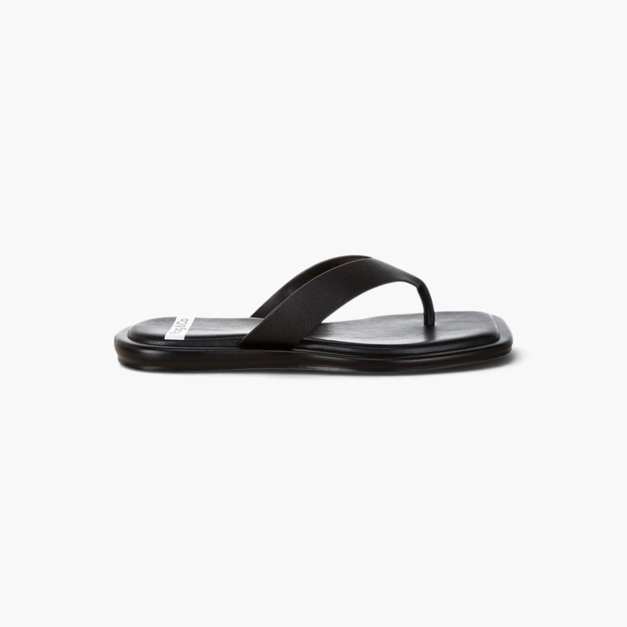 Beach Rose Co. black faux leather thong sandals with an open square toe and flat cushioned sole in side profile.