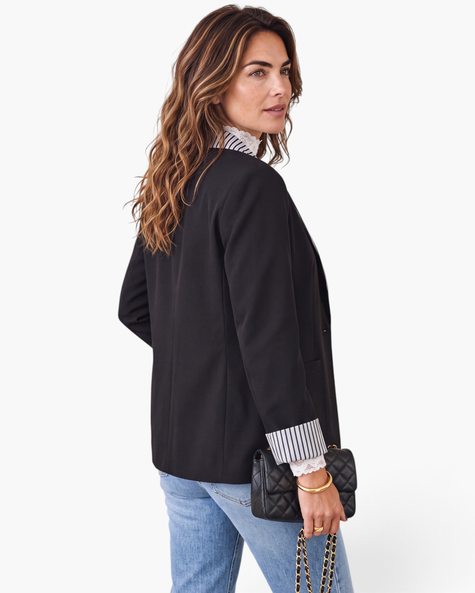 Beach Rose Co. black blazer with white striped lapels and cuffs worn by a woman with jeans and a quilted handbag