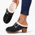 Beach Rose Co. black suede clogs with fluffy white trim, oversized buckle, and chunky block heel on a model's foot.