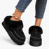 Beach Rose Co. black suede platform clogs with plush faux fur trim, moccasin stitching, and decorative tassels.
