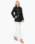 Beach Rose Co. black mid-length peacoat with toggle buttons and pockets worn by a blonde model with white trousers