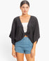 Beach Rose Co. black oversized twist knot top with deep V-neck and loose sleeves worn over a white camisole