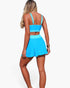 Beach Rose Co. two-piece bikini with a blue color block top and high-waisted skirted bottom on a model, back view.