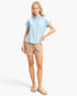 Beach Rose Co. light blue cotton button-up top with rolled sleeves and chest pocket worn with beige shorts