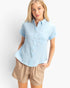 Beach Rose Co. light blue cotton button-up top with rolled sleeves and chest pocket worn by a blonde model