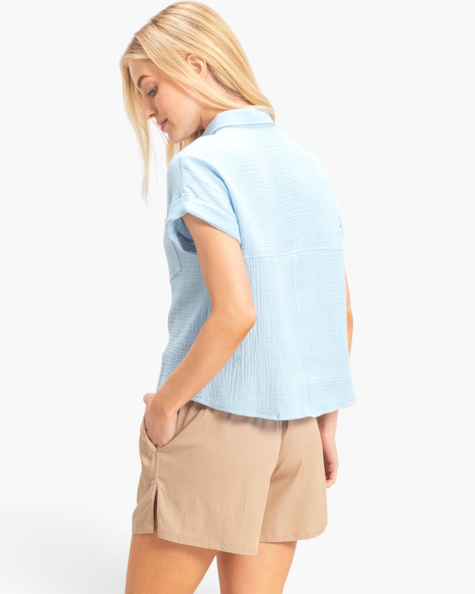 Beach Rose Co. light blue cotton button-up top with rolled sleeves worn by a woman, back view.