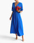 Beach Rose Co. blue pleated A-line full dress with batwing sleeves worn by a model holding a bouquet of red roses.