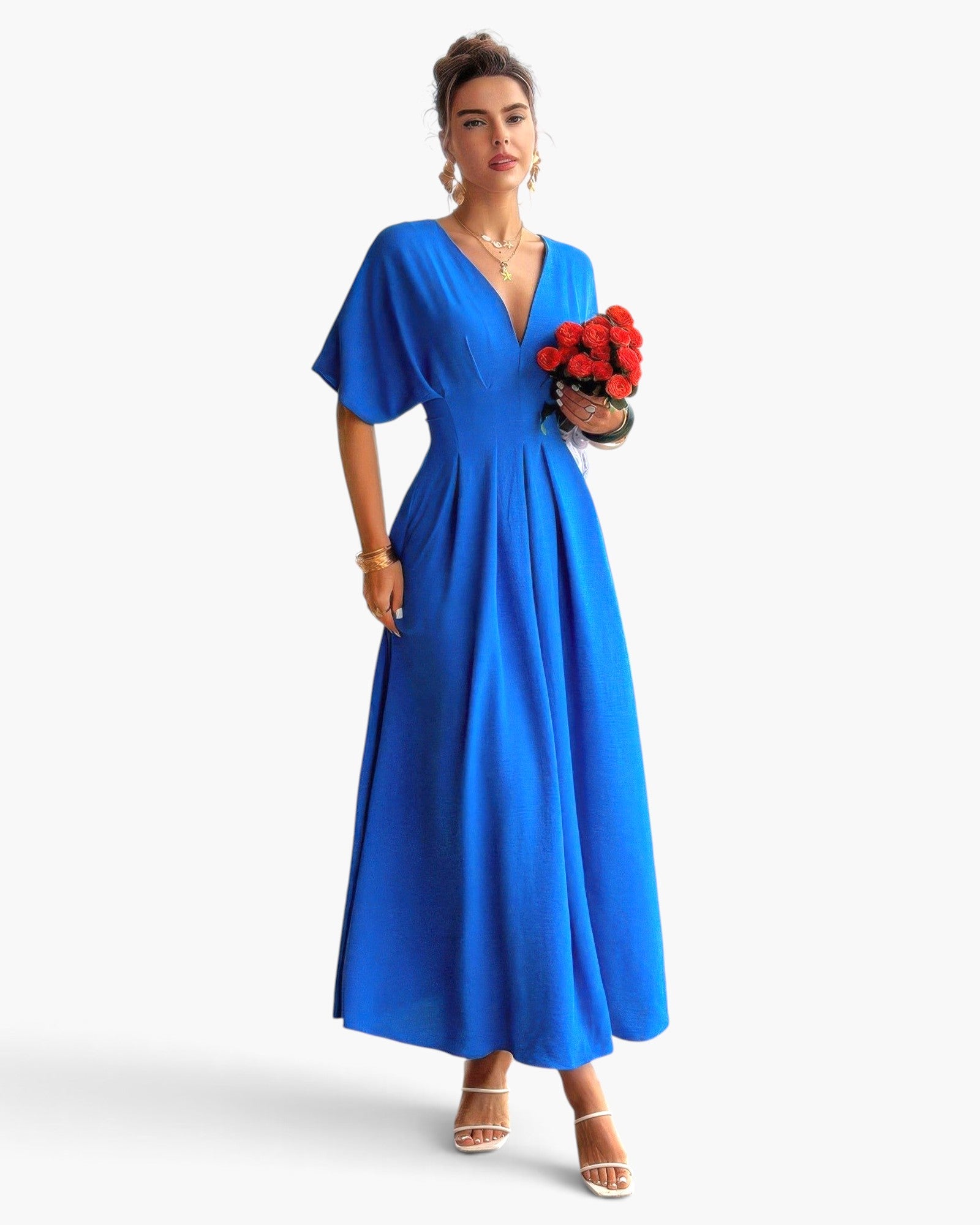 Beach Rose Co. blue pleated A-line full dress with batwing sleeves worn by a model holding a bouquet of red roses