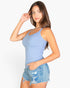 Beach Rose Co. model wearing a light blue ribbed knit cami top with a scoop neckline and denim shorts