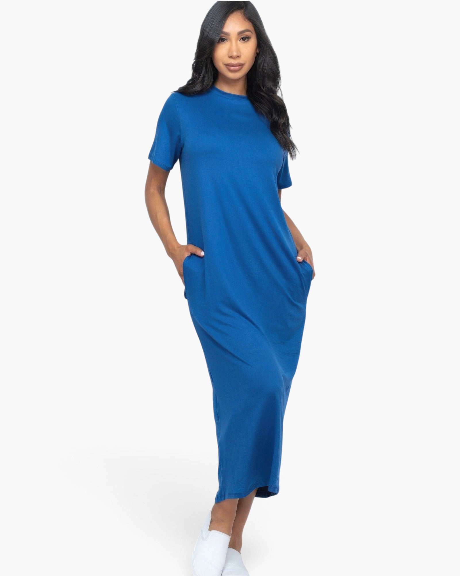 Beach Rose Co. blue jersey tee dress with short sleeves and side pockets worn by a model with white slip-on shoes.