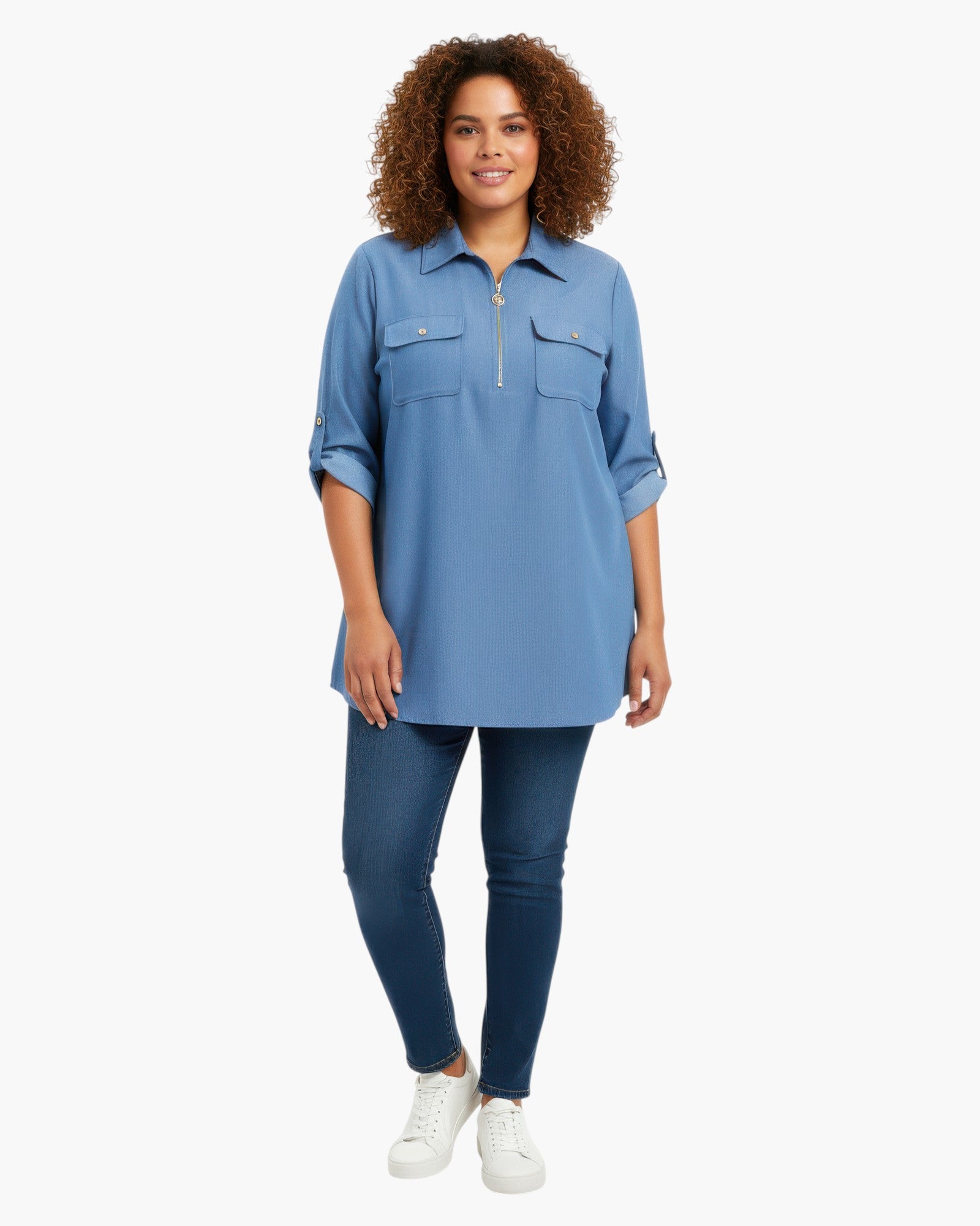 Beach Rose Co. blue zip-front tunic blouse with utility pockets and roll-tab sleeves worn by a curly-haired model.