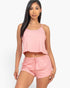 A model wearing a Beach Rose Co. blush pink ribbed strappy top and matching drawstring shorts set.