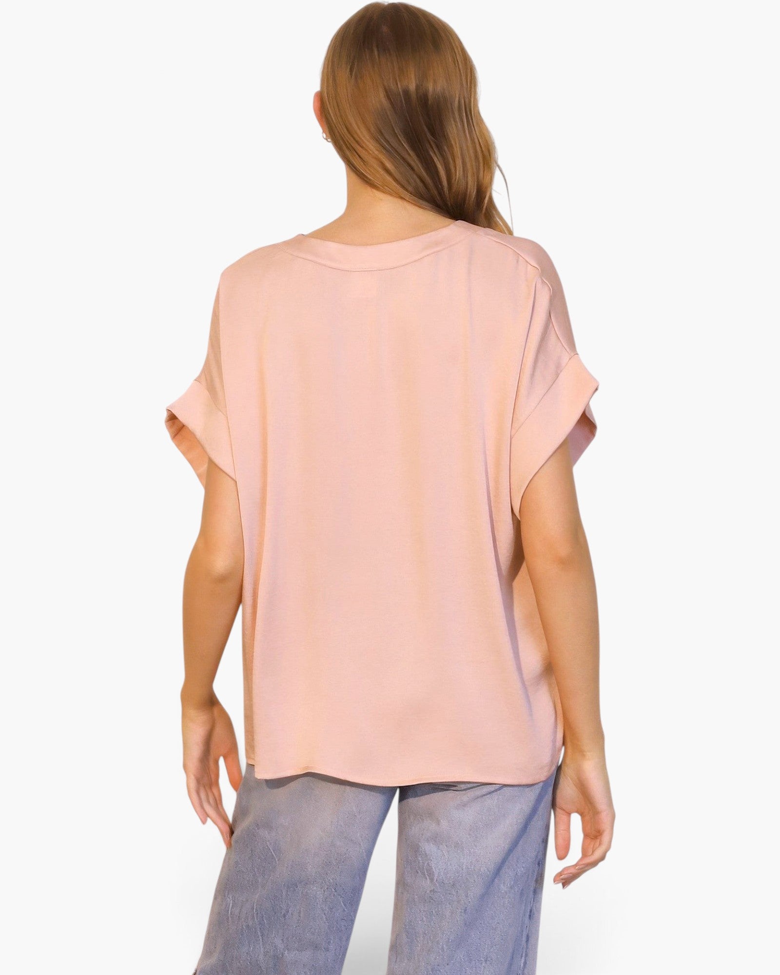 Back view of a model wearing a Beach Rose Co. blush pink washed poly silk V-neck tee with cuffed short sleeves.