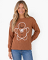 Beach Rose Co. brown crewneck sweater featuring a smiling gingerbread man graphic with a white bow on a blonde model.