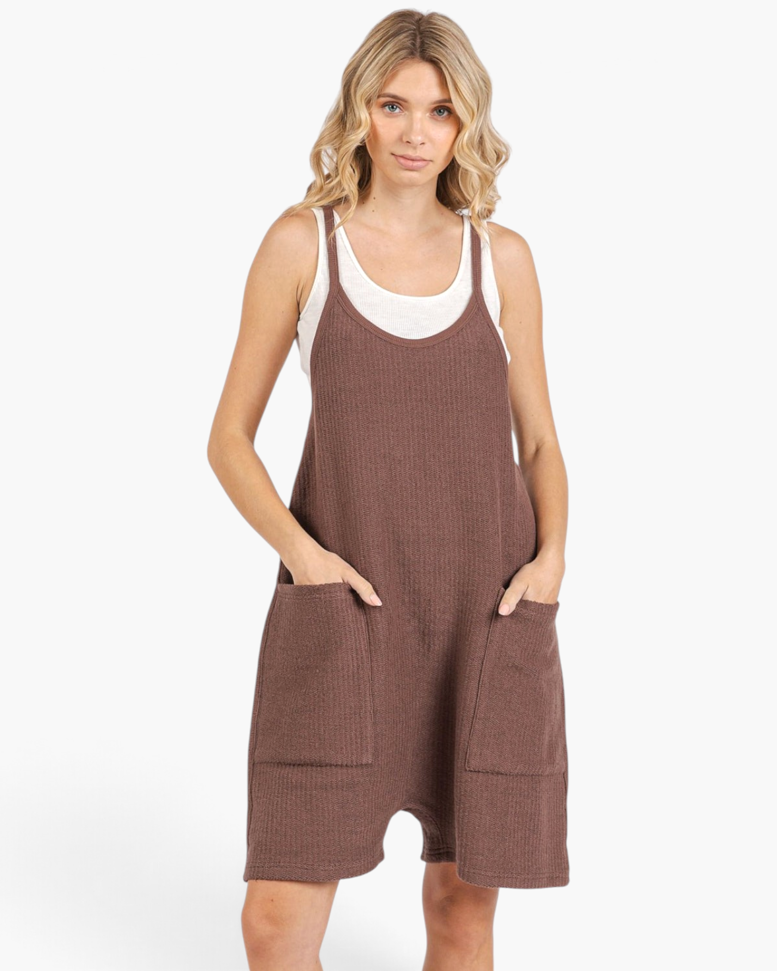Beach Rose Co. brown relaxed knit romper with wide legs, slim straps, and oversized front pockets on a blonde model.