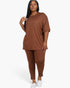 A model wearing a Beach Rose Co. plus size brown oversized t-shirt and matching leggings set with white sneakers.