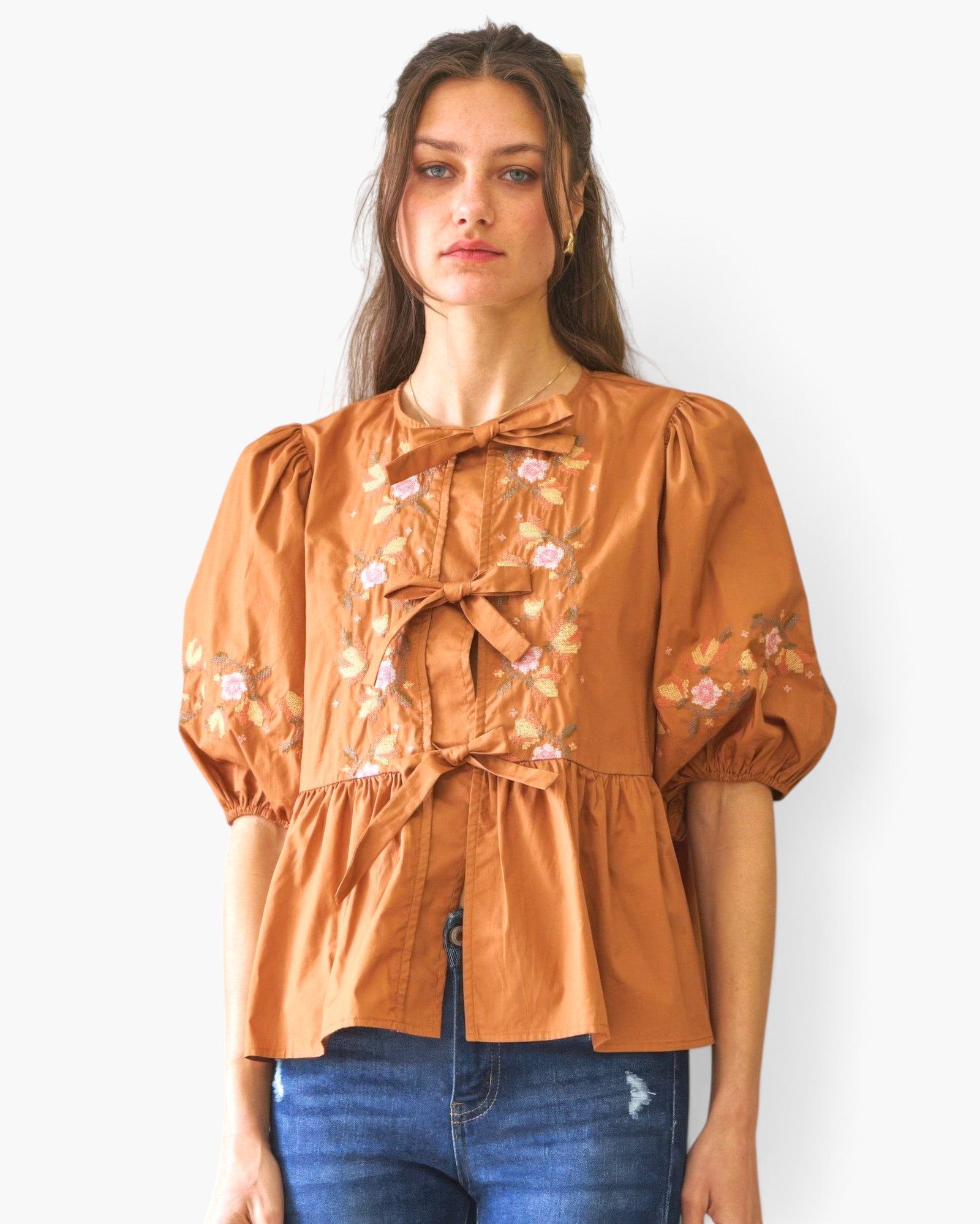 Beach Rose Co. brown poplin blouse with front ribbon ties, floral embroidery, and puff sleeves on a female model.