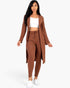 Beach Rose Co. brown ribbed long cardigan and leggings set worn by a model with a white crop top and sneakers