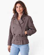 Beach Rose Co. brown short trench jacket with double-breasted buttons, wrap collar, and buckled waist belt on model.