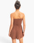 Back view of a model wearing a brown Beach Rose Co. strapless romper with a shirred waist and relaxed shorts.