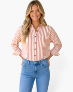 Beach Rose Co. brown and cream vertical striped button-up shirt with a pointed collar worn by a smiling model.