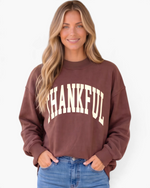 Beach Rose Co. brown mock neck sweatshirt with cream THANKFUL graphic worn by a smiling woman with blonde hair.