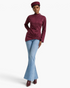 Model wearing a Beach Rose Co. burgundy asymmetrical jacket with a mock neck, shoulder snaps, and a hip buckle.