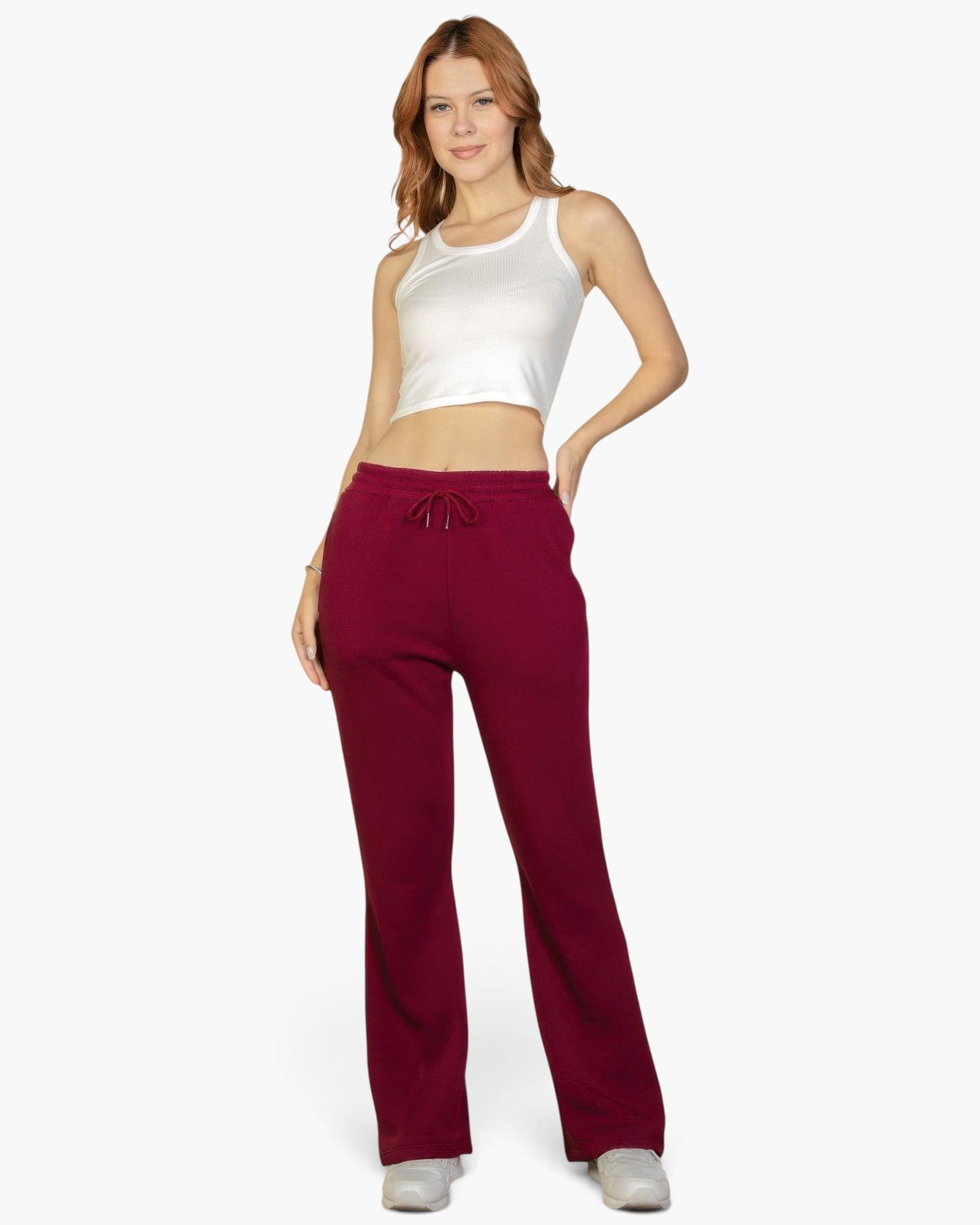 A model wearing Beach Rose Co. burgundy bootcut sweatpants with a drawstring waist and a white cropped tank top.