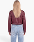 Back view of a Beach Rose Co. cropped burgundy faux leather moto jacket with a grommet belt and shoulder epaulets.