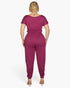 Back view of a Beach Rose Co. plus size burgundy short sleeve jumpsuit in soft stretch jersey with a drawstring waist