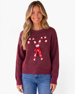 Beach Rose Co. burgundy crewneck sweater with sequin candy cane and ribbon bow design worn by a smiling blonde woman