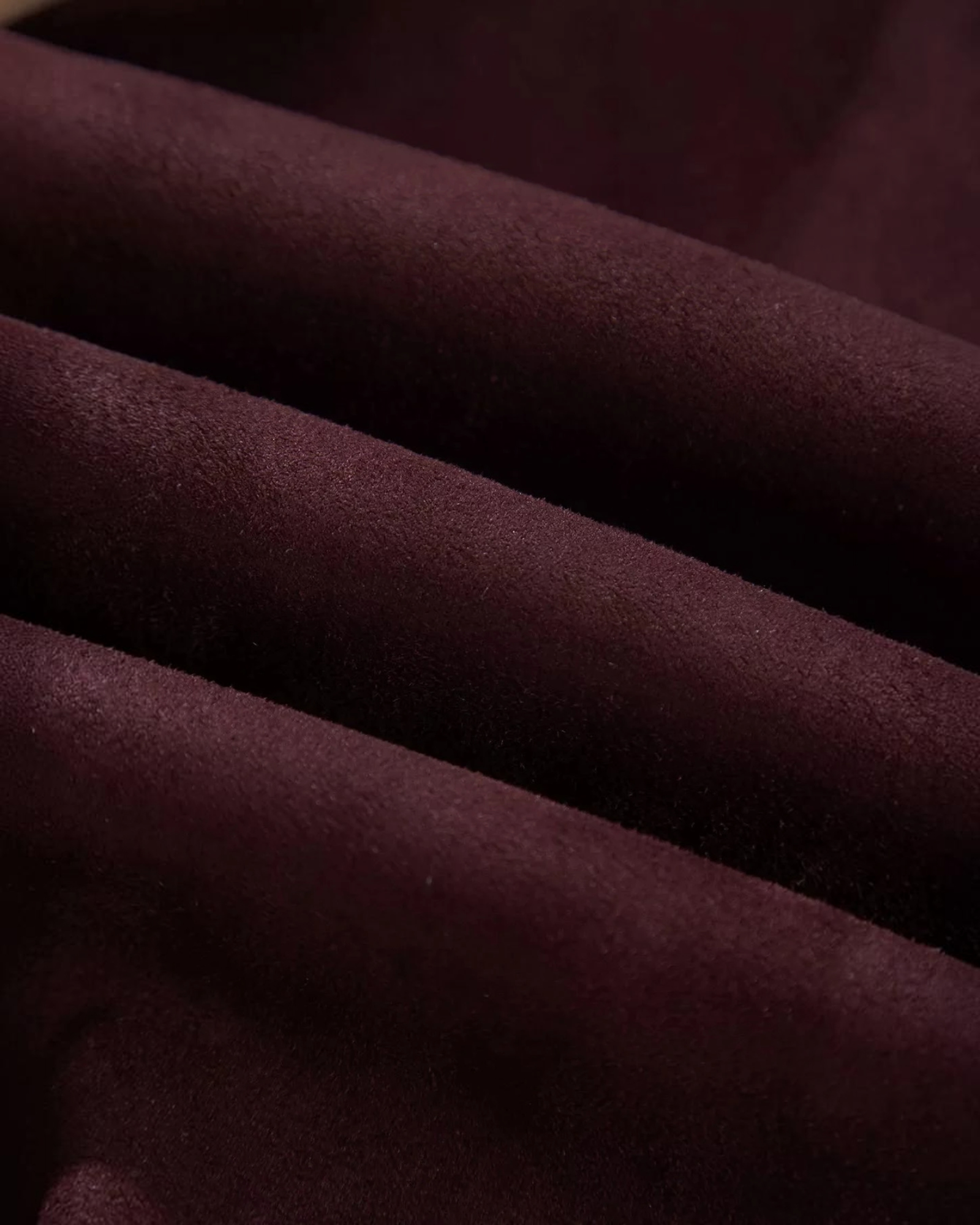 Close-up of deep burgundy suede-like polyester fabric texture for a Beach Rose Co. jacket.