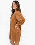 Beach Rose Co. camel corduroy mini dress with puff sleeves and gathered yoke, worn by a model in side profile view.