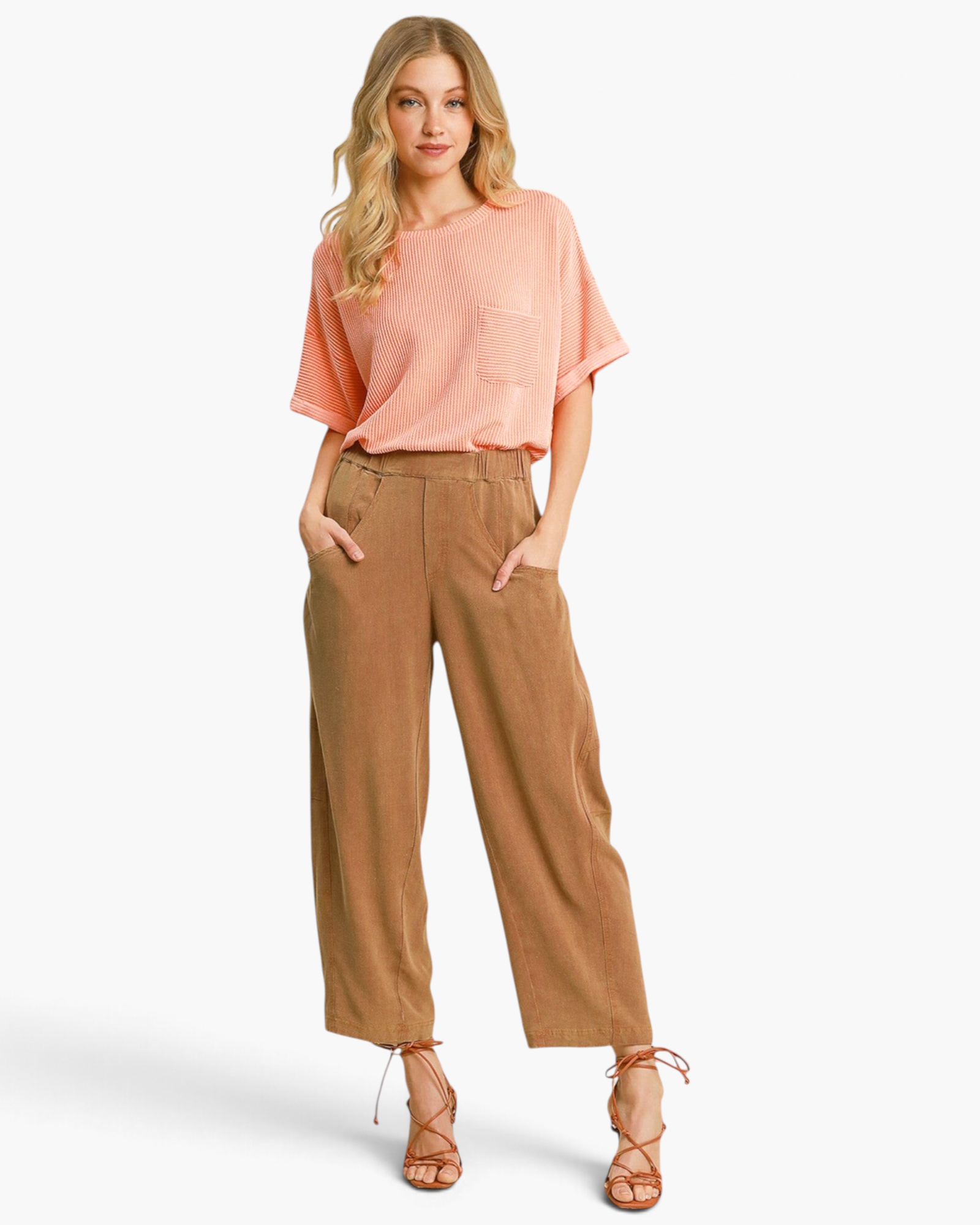 Beach Rose Co. camel linen-blend barrel-leg pants with curved pockets worn by a model with a peach ribbed top.