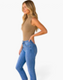 Beach Rose Co. camel ribbed sleeveless mock-neck top worn by a blonde model with blue jeans in a side profile view.