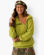 Beach Rose Co. chartreuse ribbed knit sweater with an asymmetrical zipper, worn by a smiling model in a patterned hat.