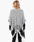 Beach Rose Co. fuzzy black and white chevron pattern ruana worn over a black long-sleeve top, back view.