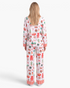 Beach Rose Co. white Christmas print pajama set with red and green festive motifs and striped trim, back view.
