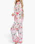 Beach Rose Co. white viscose pajama set with festive Christmas print and red striped trim on a model, side view.