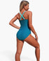 Beach Rose Co. one-piece color block swimsuit with teal body and light blue crisscross straps on a blonde model