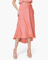 Beach Rose Co. coral washed poly silk midi swing skirt with a fluid drape and high-low hem worn with platform heels