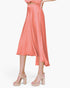 Beach Rose Co. coral washed poly silk midi swing skirt with a fluid drape and high-low hemline on a model.