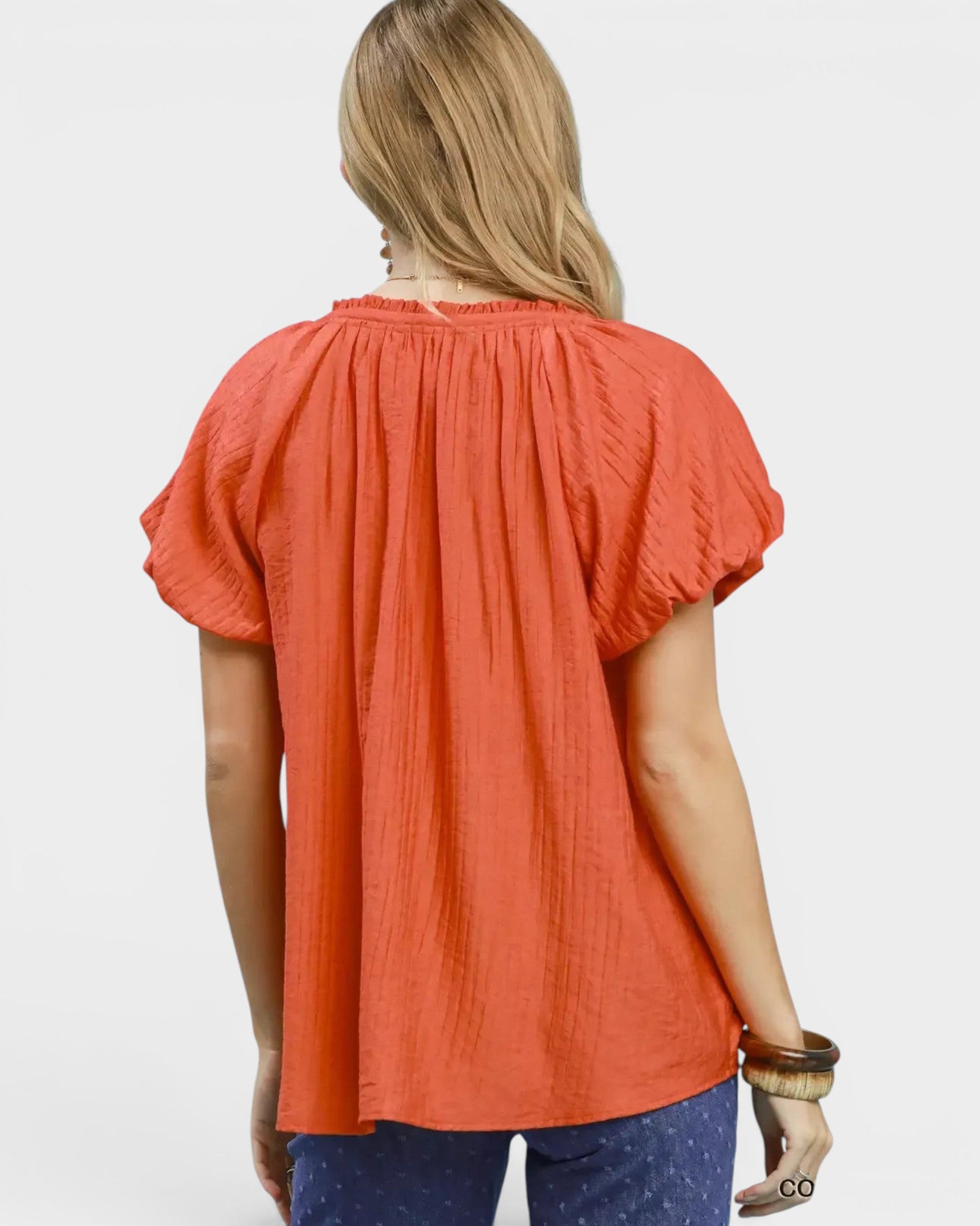 Beach Rose Co. coral orange puff sleeve blouse with gathered V-neckline and textured fabric.