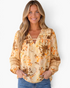 Beach Rose Co. cream floral and paisley blouse with billowy sleeves, lace inserts, and ladder trim on a smiling model.
