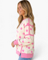Beach Rose Co. cream sweatshirt with pink polka dots, exposed seams, and ribbed trim worn by a smiling blonde woman.