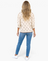 Beach Rose Co. cream cotton sweater with brown polka dots, long sleeves, and scalloped hem, back view on a model.