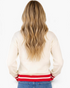 Beach Rose Co. cream sweater with red striped hem worn by a woman with long blonde hair, back view