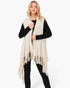 Beach Rose Co. cream knit vest with embossed dotted texture and tassel fringe hem worn over a black long sleeve top