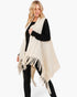 Beach Rose Co. cream knit vest with embossed dotted pattern and tassel fringe worn over a black long sleeve top